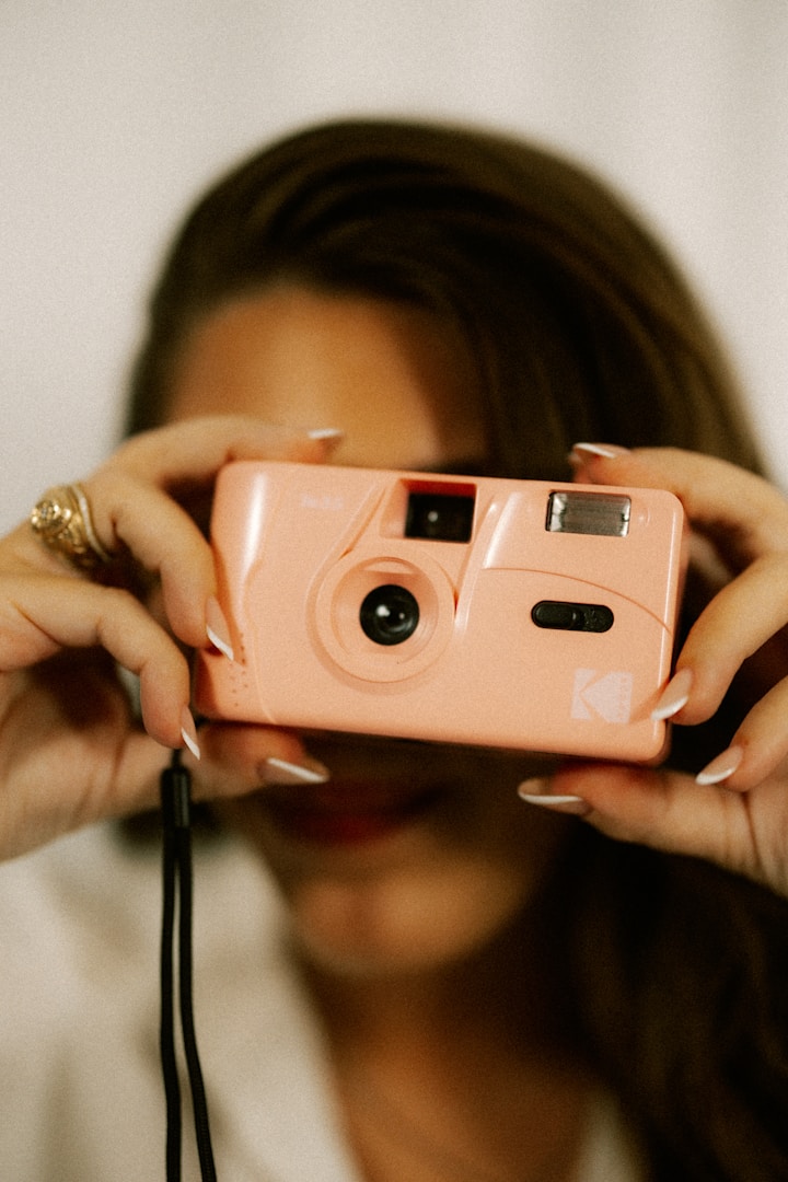 Woman holds a pink camera, ready to take a picture.