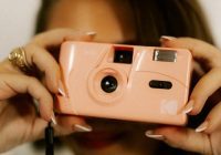 Woman holds a pink camera, ready to take a picture.